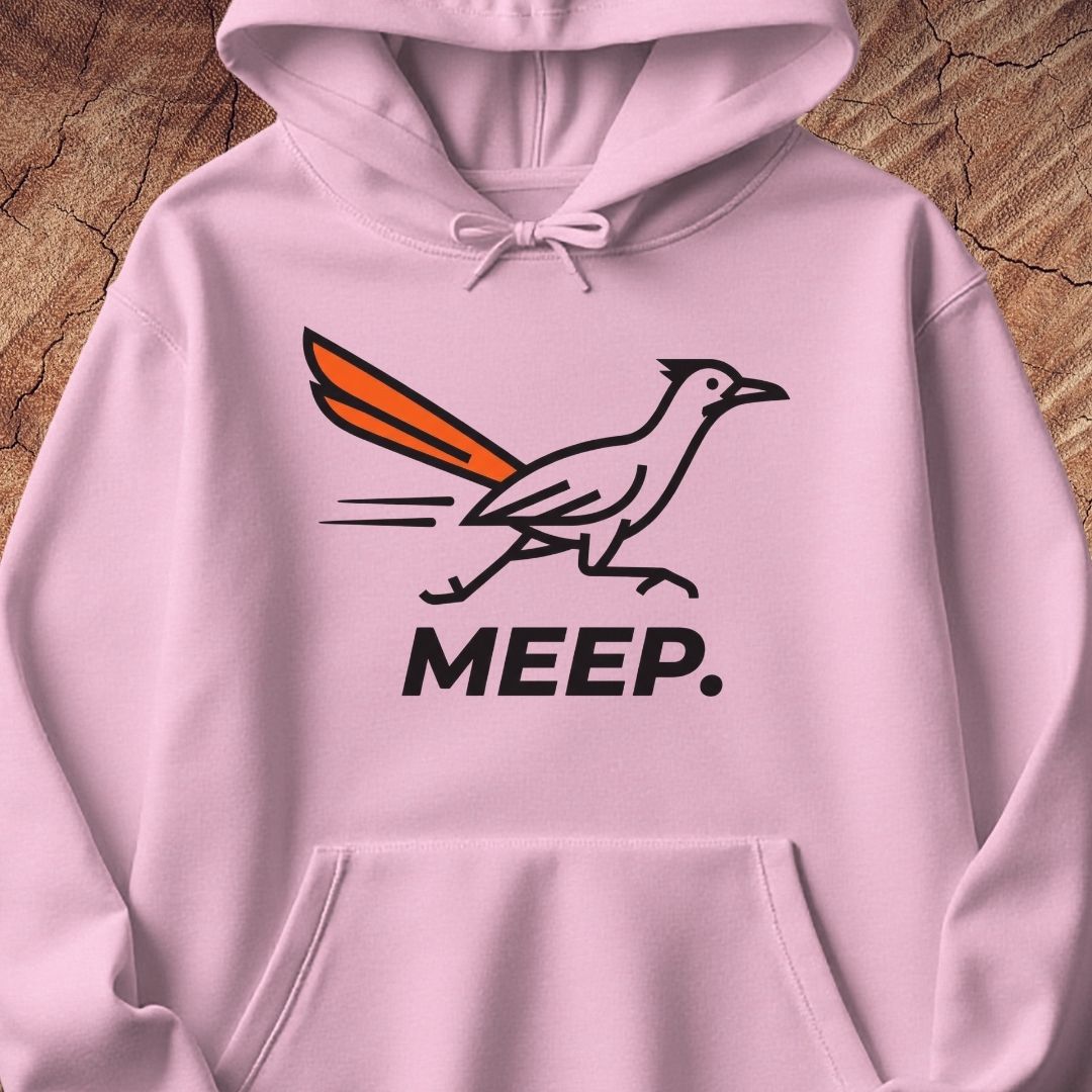 A light pink pullover hoodie featuring a graphic of a roadrunner with an orange tail and the word 'MEEP.' printed below in black, displayed against a rustic wood background.