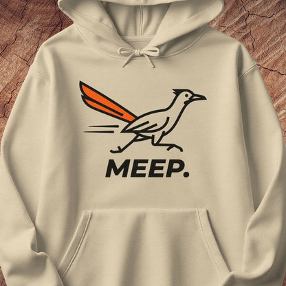 A beige pullover hoodie featuring a graphic of a roadrunner with an orange tail and the word 'MEEP.' printed below in black, displayed against a rustic wood background.