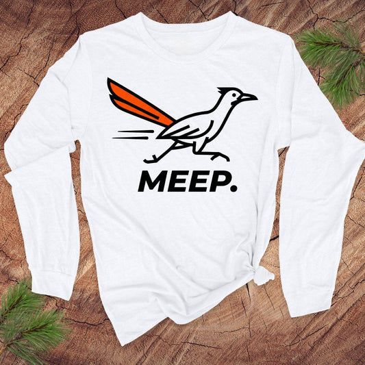 White long-sleeve shirt with a graphic of a roadrunner and 'MEEP.' text on a wooden surface.
