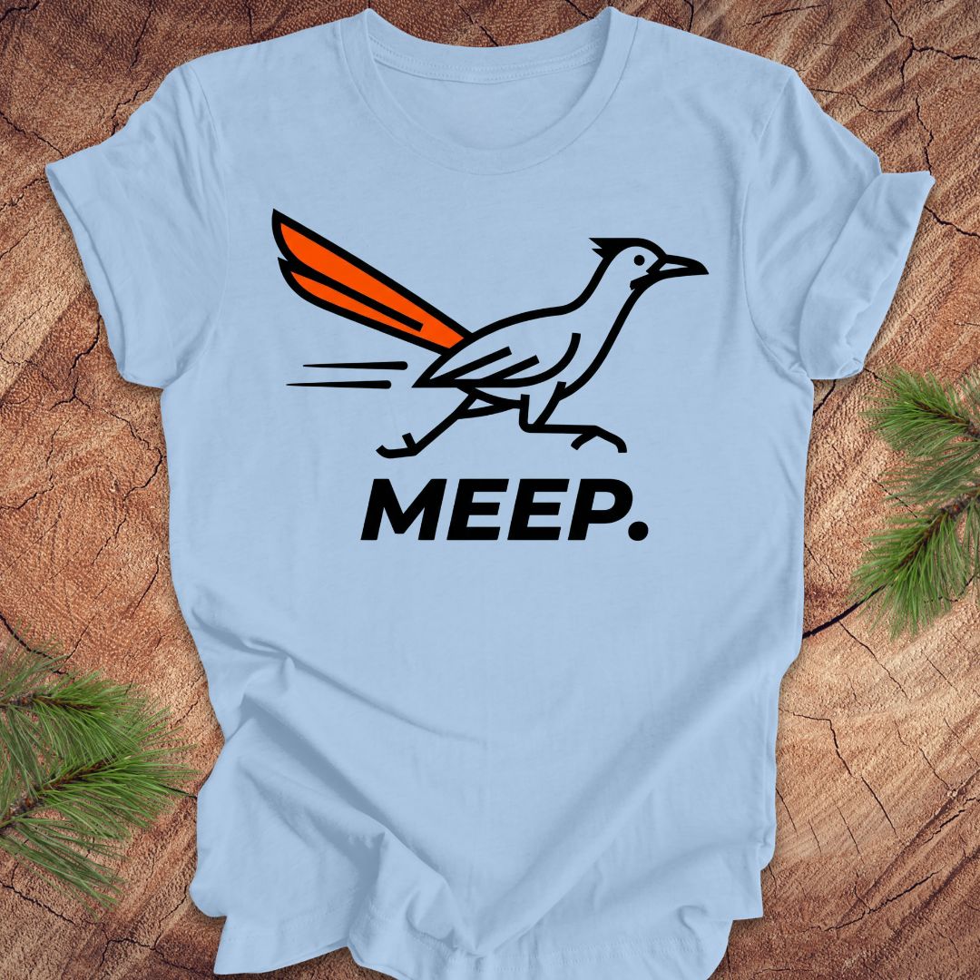 Blue t-shirt with a graphic of a roadrunner and 'MEEP.' text on a wooden surface.