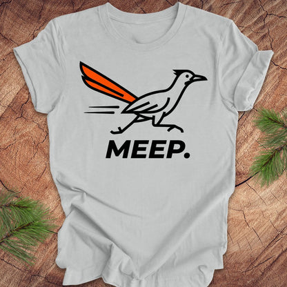 Gray t-shirt with a graphic of a roadrunner and 'MEEP.' text on a wooden surface.