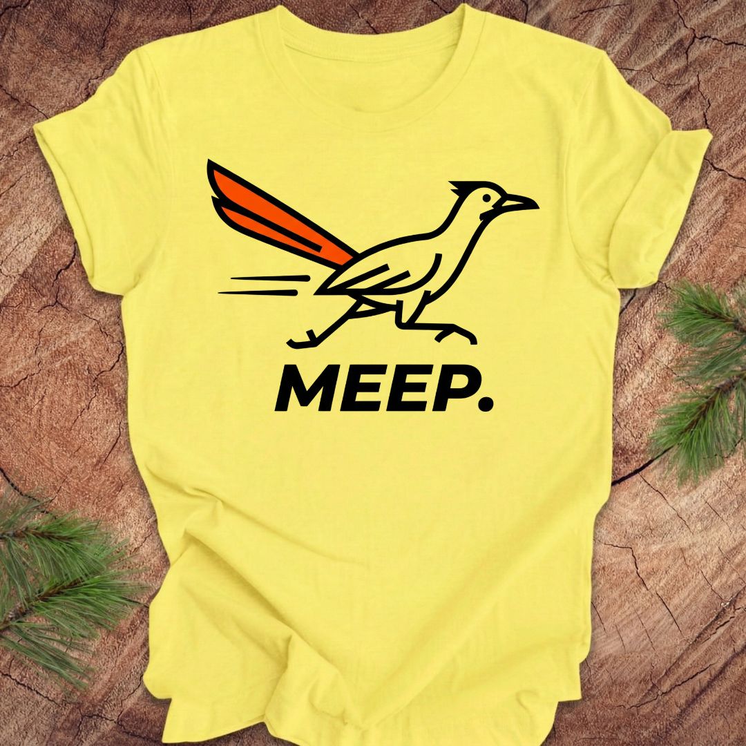 Yellow t-shirt with a graphic of a roadrunner and 'MEEP.' text on a wooden surface.