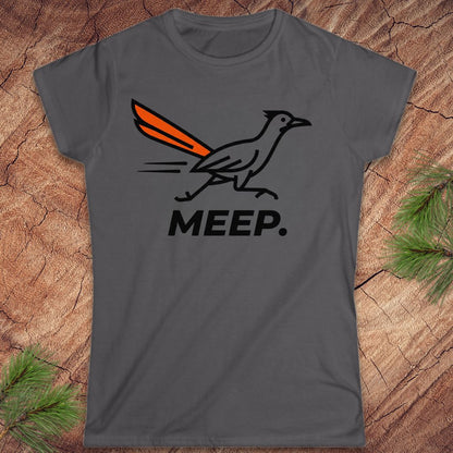 A dark gray short-sleeve t-shirt with a graphic of a roadrunner bird with an orange tail and the word 'MEEP.' printed below it, displayed flat on a rustic wood background with pine branches.