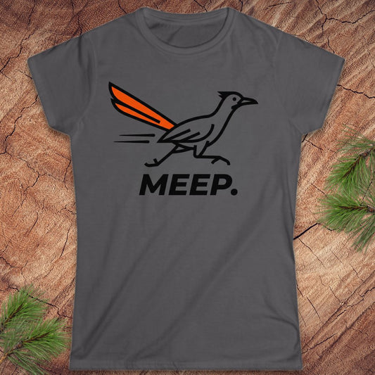A dark gray short-sleeve t-shirt with a graphic of a roadrunner bird with an orange tail and the word 'MEEP.' printed below it, displayed flat on a rustic wood background with pine branches.