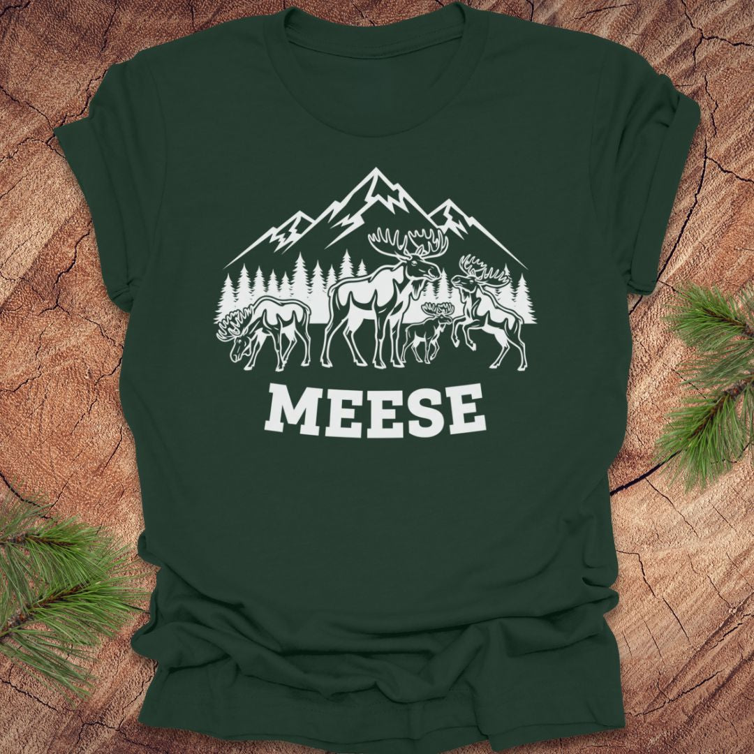 Forest green t-shirt with moose, trees and mountains with text "meese"on a wood background. 