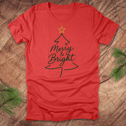 Red t-shirt with Christmas tree design and 'Merry & Bright' text on a wooden surface.