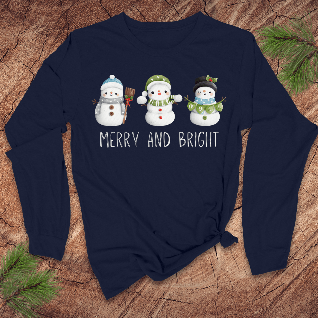 Navy blue long-sleeve shirt with snowman design and 'Merry and Bright' text on a wooden surface.