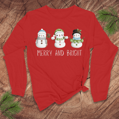 Red long-sleeve shirt with snowman design and 'Merry and Bright' text on a wooden surface.