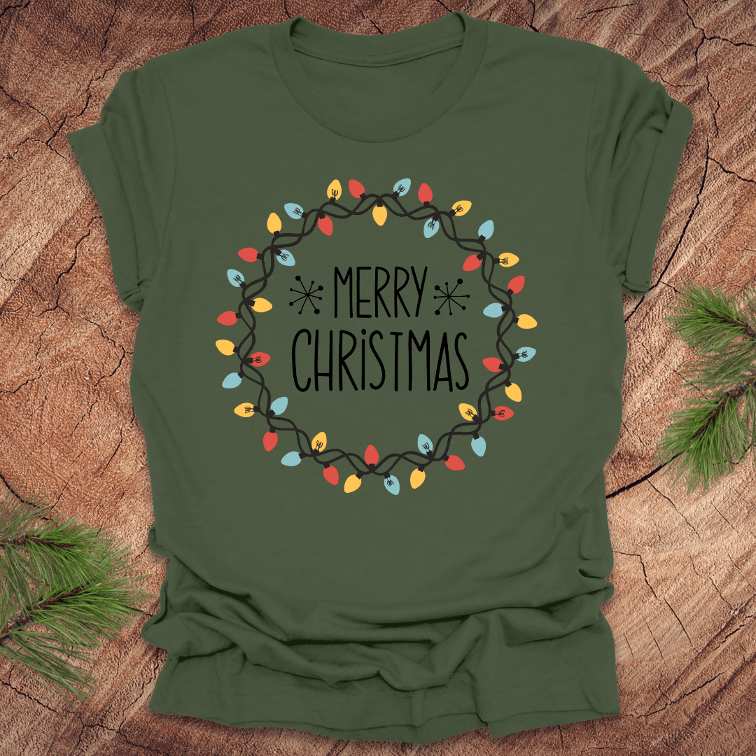 Green t-shirt with 'Merry Christmas' design on a wooden surface