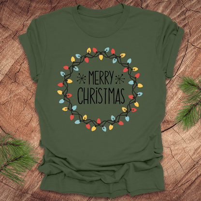 Green t-shirt with 'Merry Christmas' design on a wooden surface
