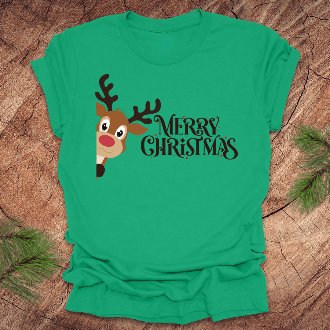 Green t-shirt with a reindeer peeking out from the side and 'Merry Christmas' text on a wooden surface.