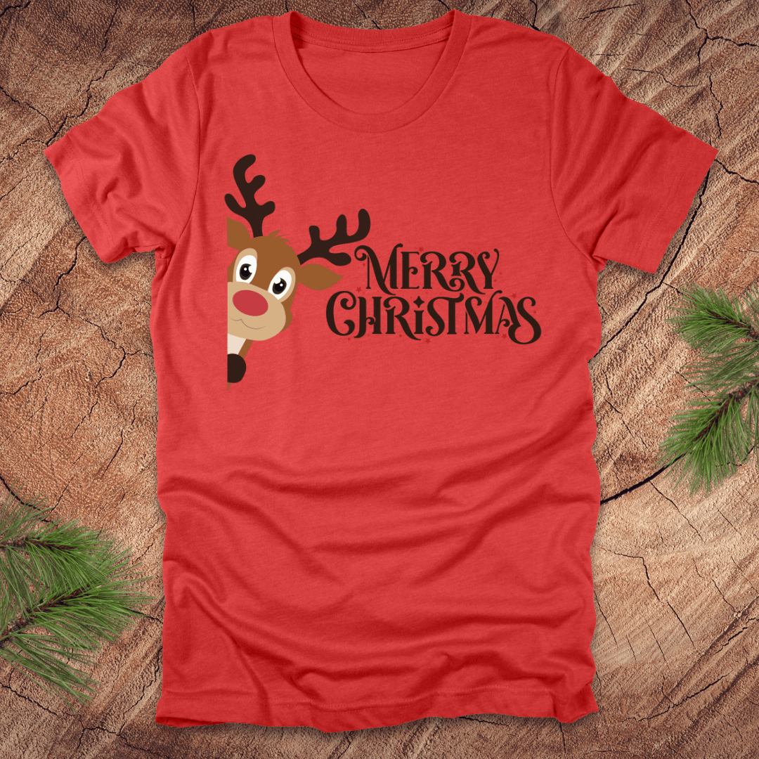 Red t-shirt with a reindeer peeking out from the side and 'Merry Christmas' text on a wooden surface.