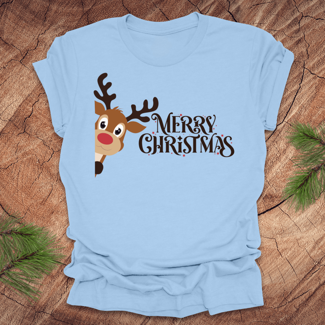 Light blue t-shirt with a reindeer peeking out from the side and 'Merry Christmas' text on a wooden surface.