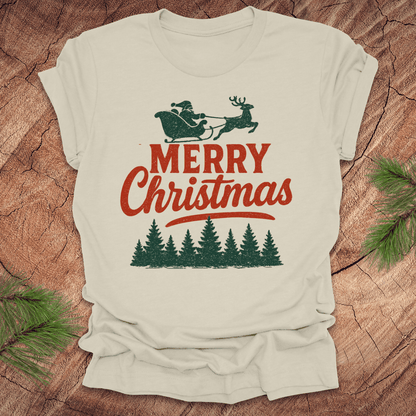 Beige t-shirt with 'Merry Christmas' design featuring Santa and reindeer on a wooden surface.