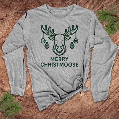 Gray long-sleeve shirt with 'Merry Christmoose' design on a wooden surface with pine branches.