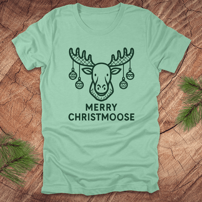 Light green t-shirt with a moose graphic and 'Merry Christmoose' text on a wooden surface.