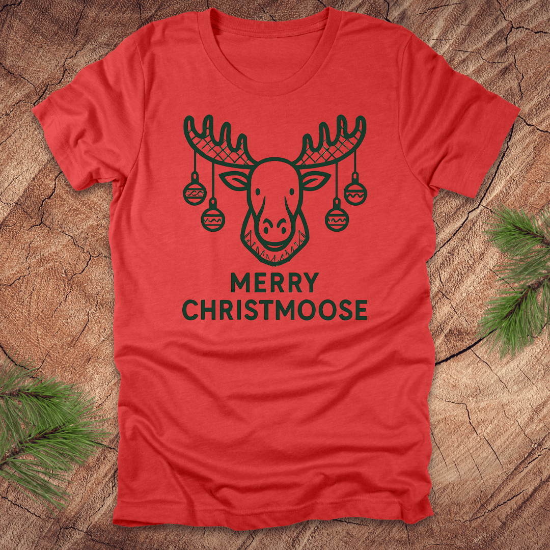 Red t-shirt with a moose graphic and 'Merry Christmoose' text on a wooden surface.