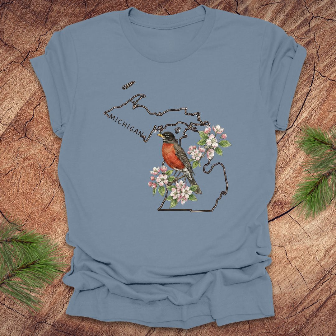 Steel blue t-shirt with Michigan-themed design featuring a robin and apple blossom on a wooden surface.