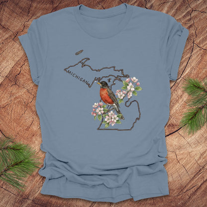 Steel blue t-shirt with Michigan-themed design featuring a robin and apple blossom on a wooden surface.