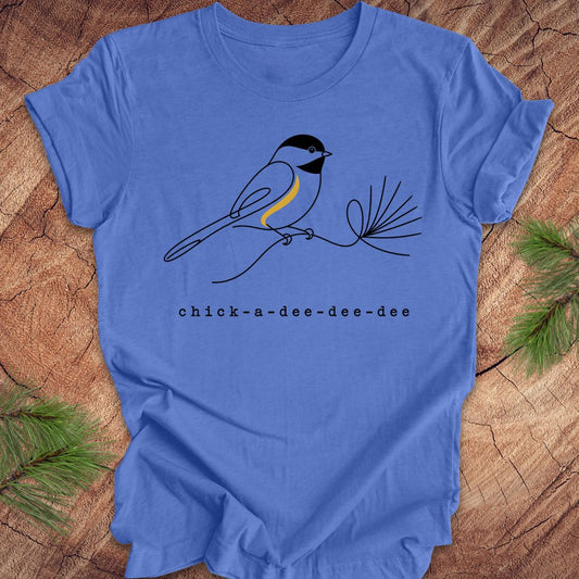 Blue t-shirt with a chickadee design and 'chick-a-dee-dee-dee' text on a wooden surface.