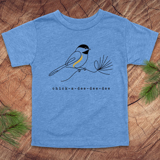 A kids' heather blue short-sleeve t-shirt featuring a black and white chickadee bird with a yellow chest, perched on a pine branch. Below the bird is the text 'chick-a-dee-dee-dee'.