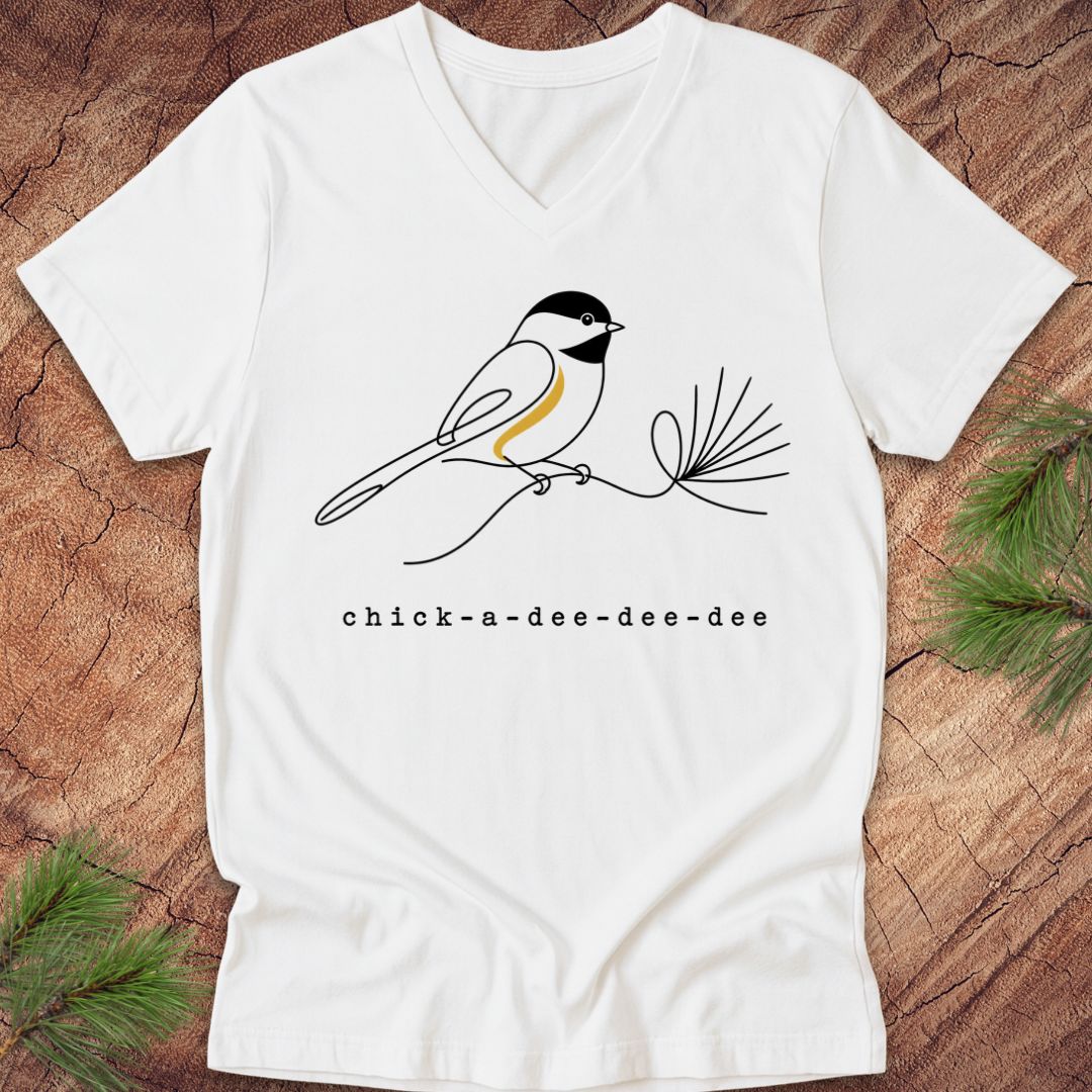 White t-shirt with a chickadee design and 'chick-a-dee-dee-dee' text on a wooden surface.