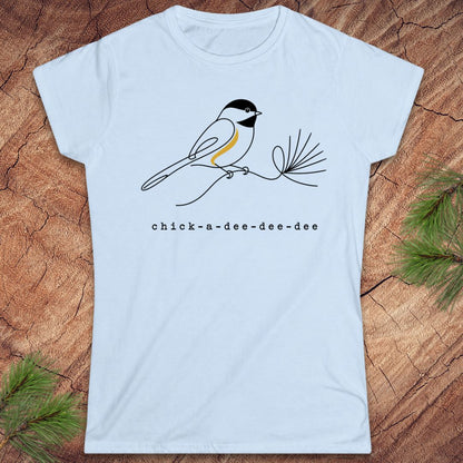 White t-shirt with a chickadee design and 'chick-a-dee-dee-dee' text on a wooden surface.