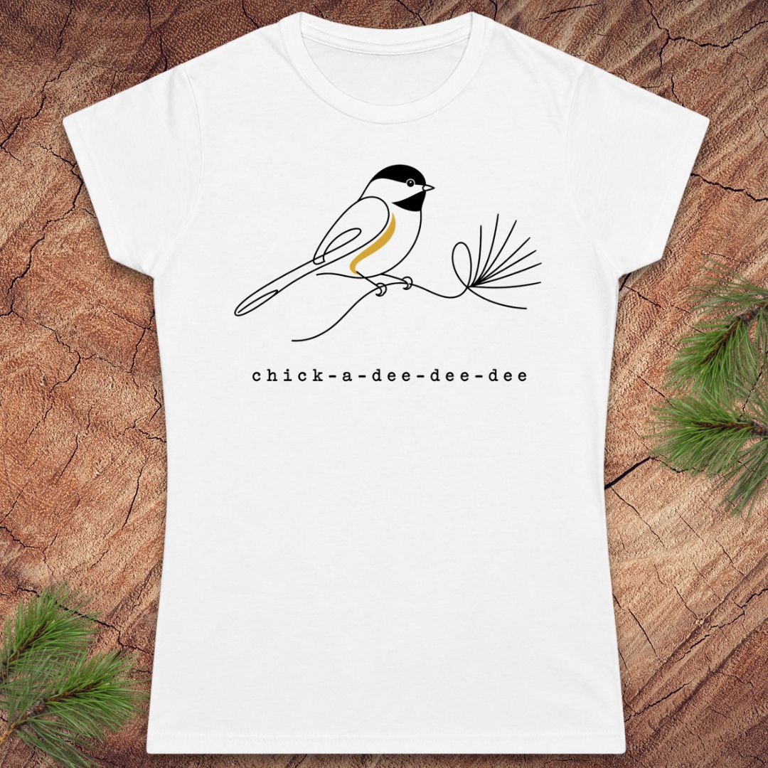 White t-shirt with a chickadee design and 'chick-a-dee-dee-dee' text on a wooden surface.