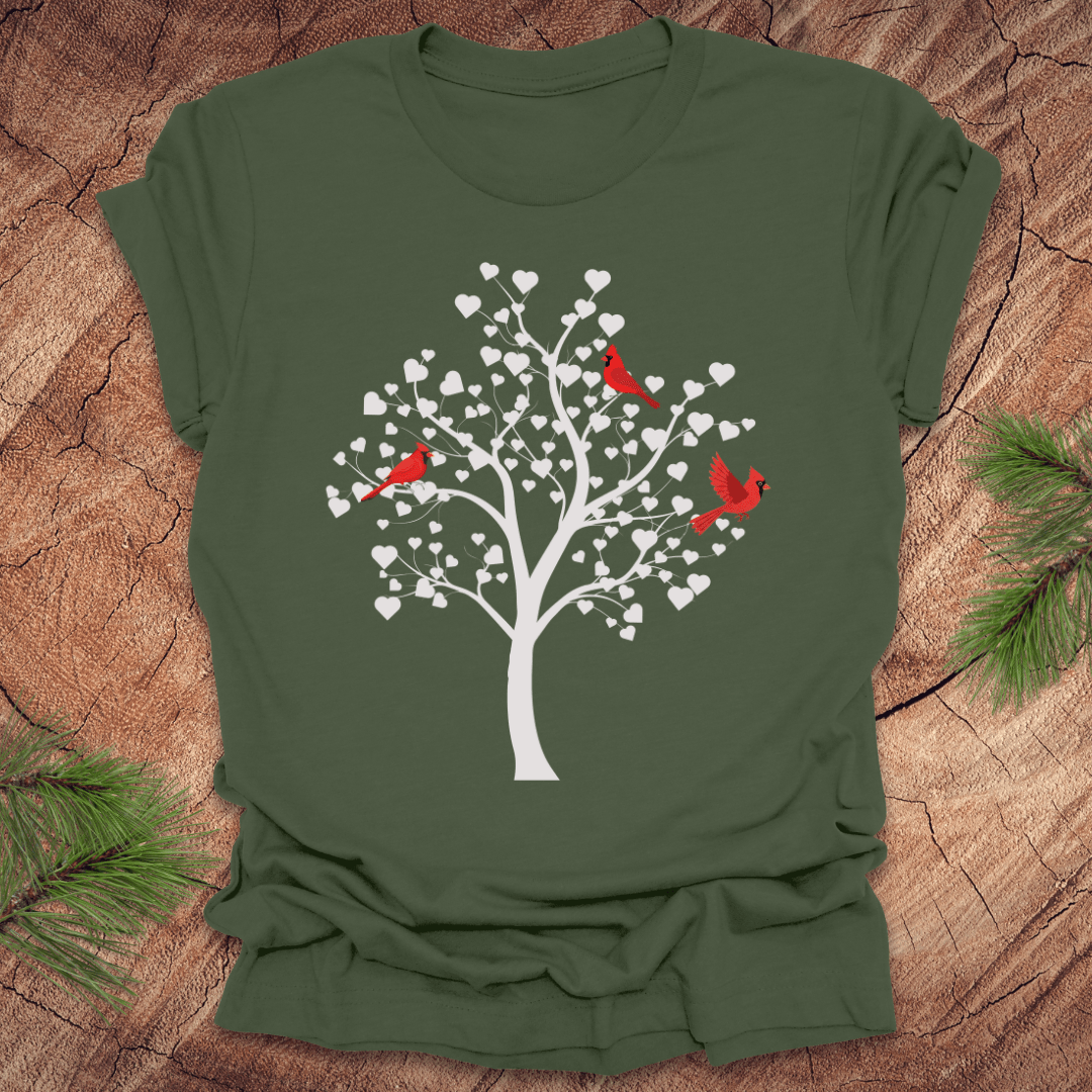 Green t-shirt with a tree design featuring cardinals and white hearts on a wooden surface.