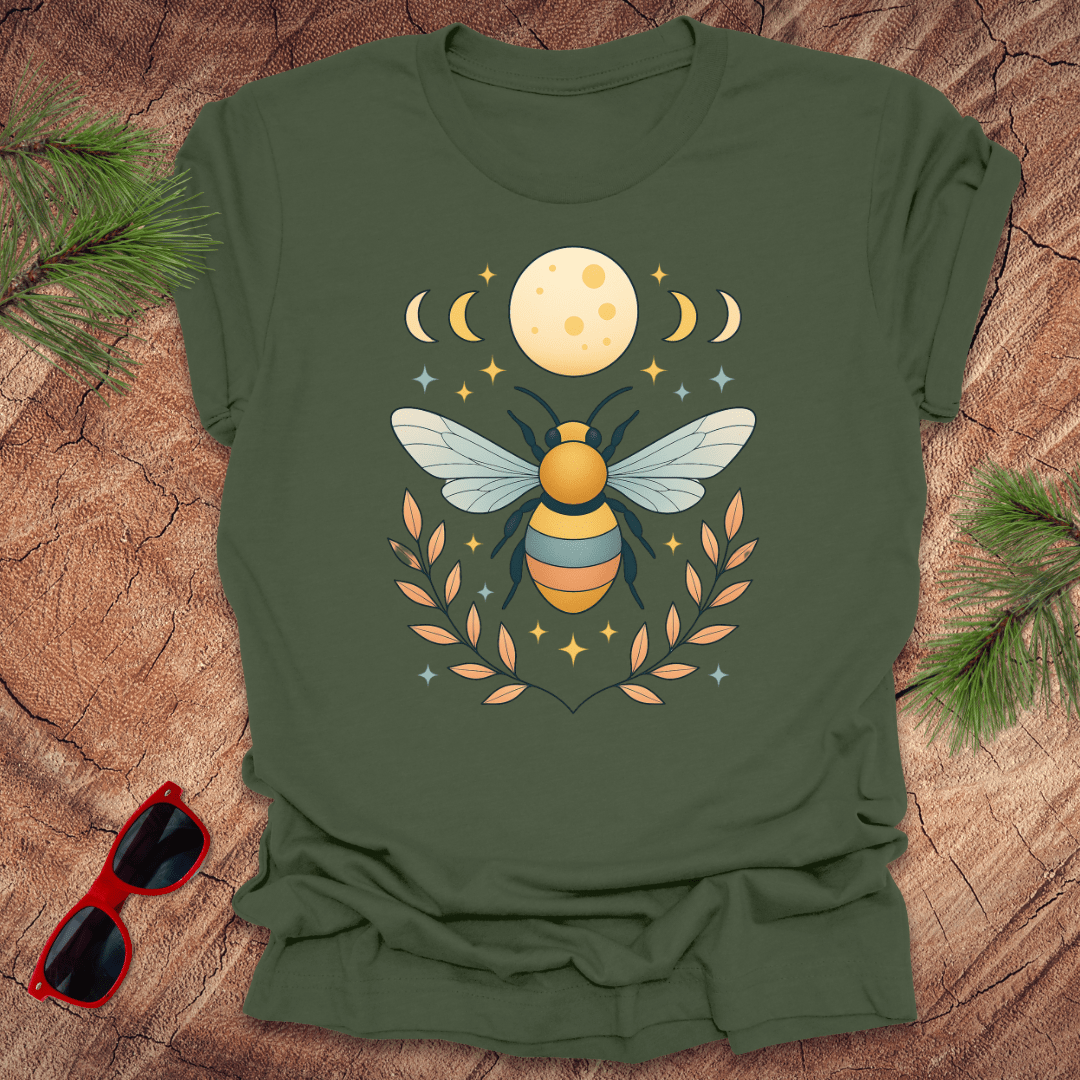 Green tshirt with a bee and moon graphic on a wood background.