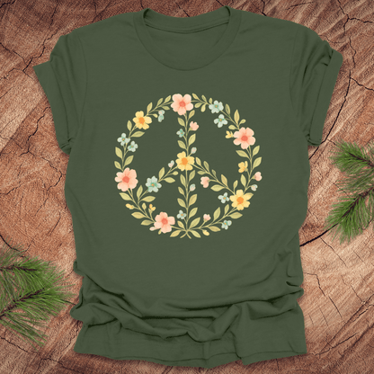 Green t-shirt with a peace sign made of flowers on a wood background.