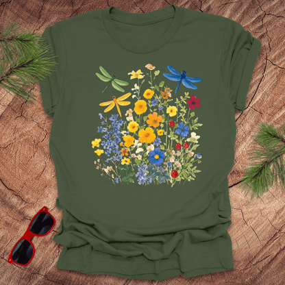 Green t-shirt with floral and dragonfly design on a wooden surface with sunglasses.