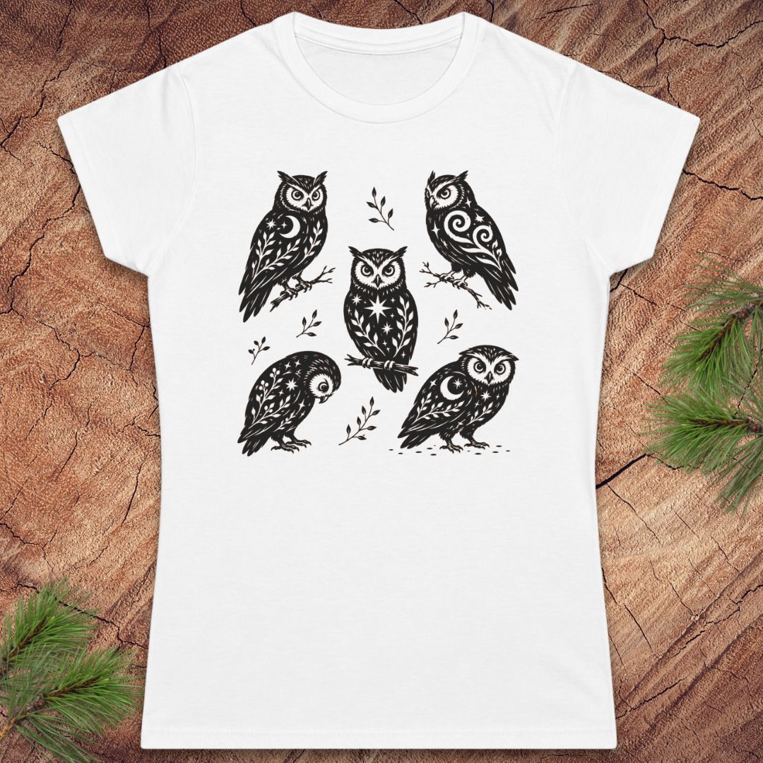 White women's t-shirt with 5 owls with moons and star decorations, on a wood background.
