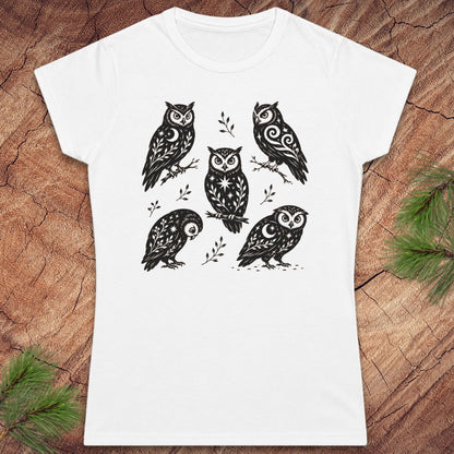 White women's t-shirt with 5 owls with moons and star decorations, on a wood background.
