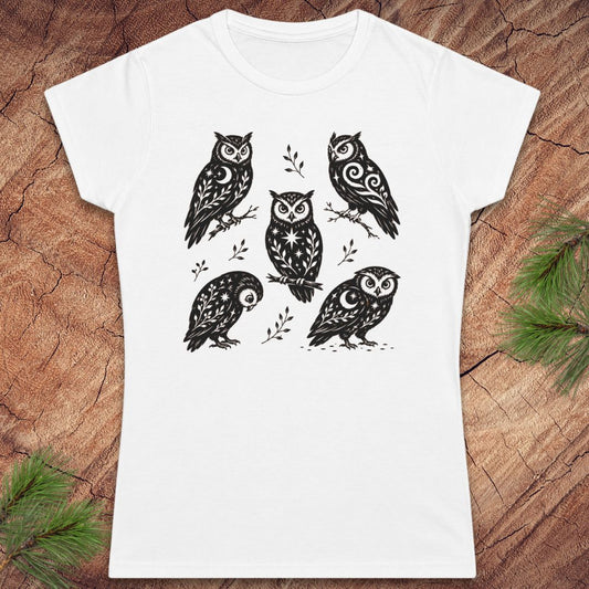 White women's t-shirt with 5 owls with moons and star decorations, on a wood background.