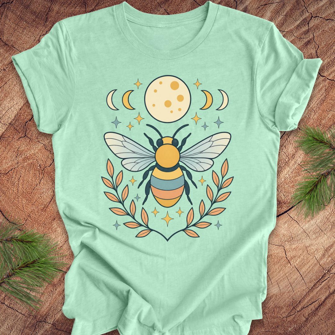 Mint green t-shirt with a bee and moon design on a wooden surface