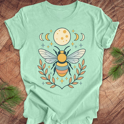 Mint green t-shirt with a bee and moon design on a wooden surface