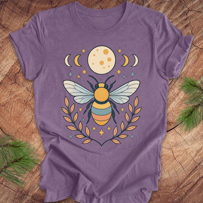 Purple t-shirt with a bee and moon design on a wooden surface