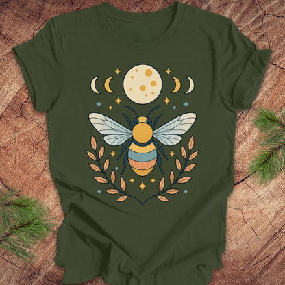 Green t-shirt with a bee and moon design on a wooden surface