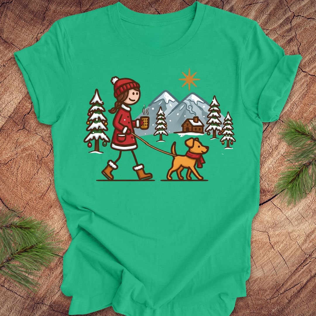 Green t-shirt with a winter scene design featuring a person and dog on a leash, set against a wooden background.