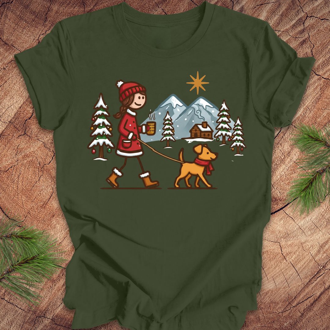 Green t-shirt with a winter scene design featuring a person and dog on a leash, placed on a wooden surface.