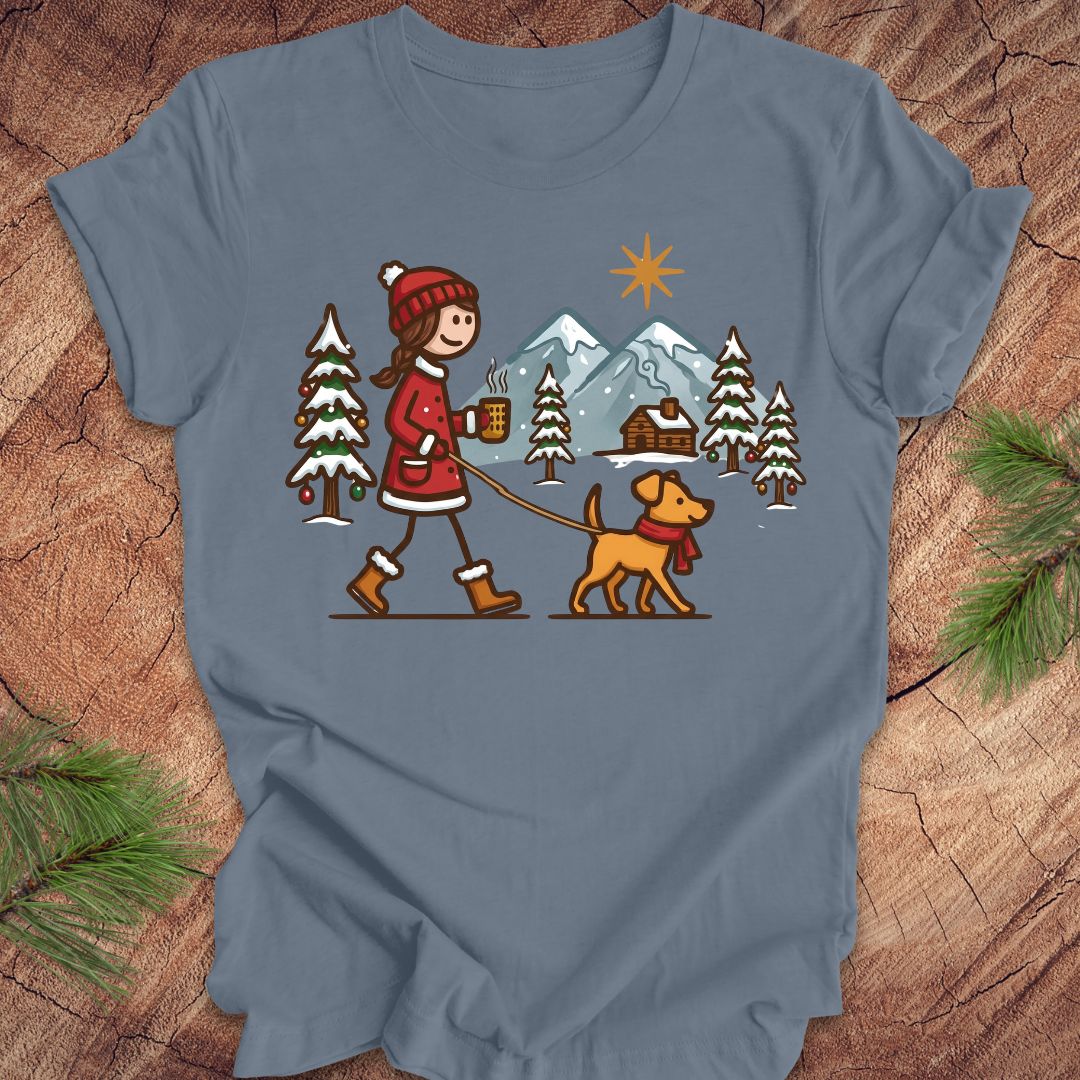Blue t-shirt with a graphic of a person walking a dog in a winter landscape on a wooden surface.