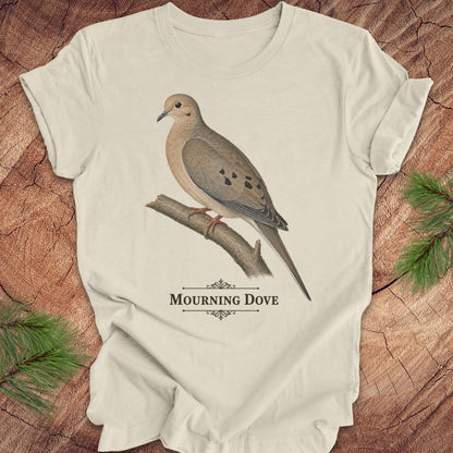Beige t-shirt with a mourning dove bird and text on a wood background.