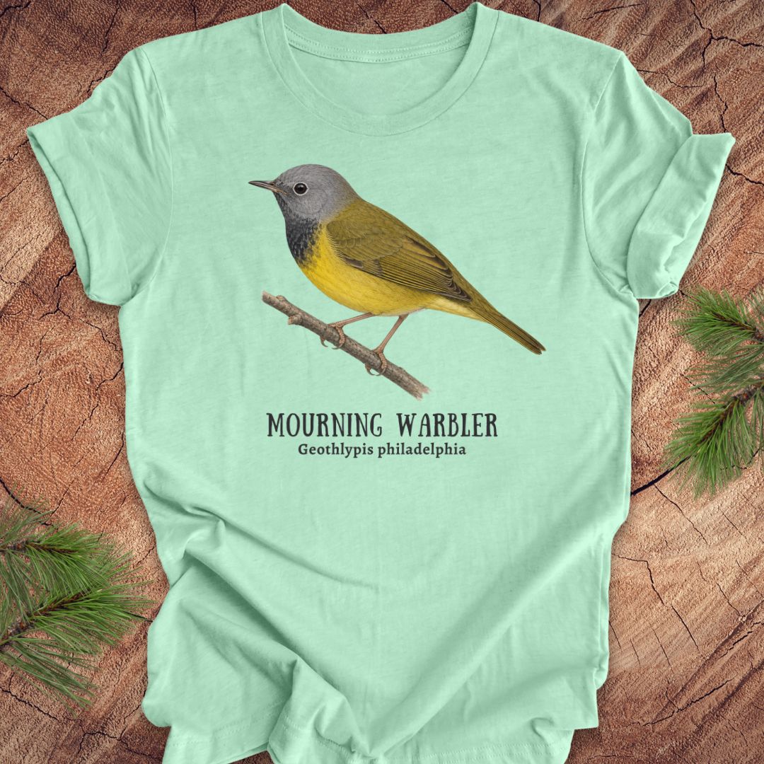 Light green t-shirt with a mourning warbler illustration and text on a wooden surface