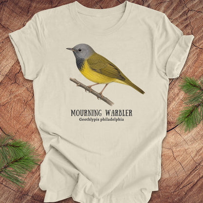 Beige t-shirt with a mourning warbler illustration and text on a wooden surface