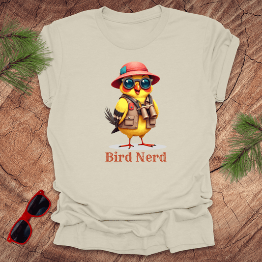 Beige t-shirt with an animated goldfinch in birdwatcher gear and text, 'Bird nerd' on a wood background.