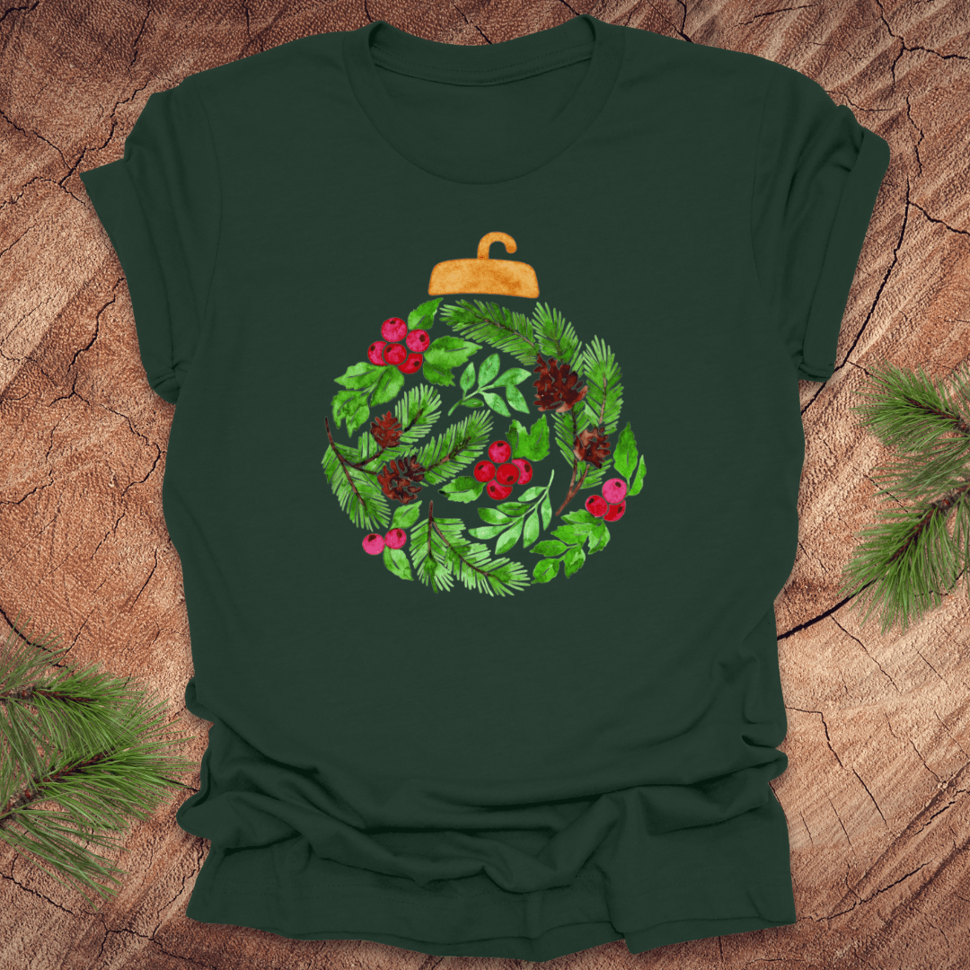 Green t-shirt with a Christmas ornament design featuring greenery and berries on a wooden surface.