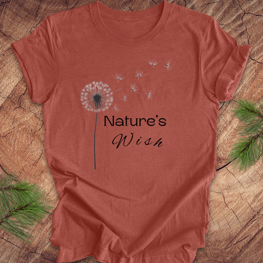 Red t-shirt with 'Nature's Wish' text and dandelion graphic on a wooden surface.