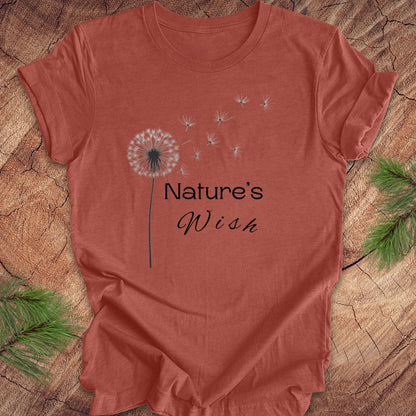 Red t-shirt with 'Nature's Wish' text and dandelion graphic on a wooden surface.