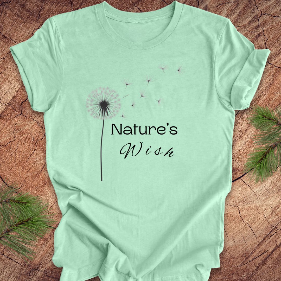 Mint green t-shirt with 'Nature's Wish' text and dandelion graphic on a wooden surface.